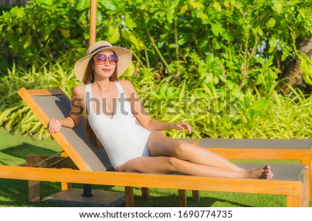 Portrait beautiful young asian woman happy smile relax sit on chair around sea ocean and outdoor swimming pool in resort hotel