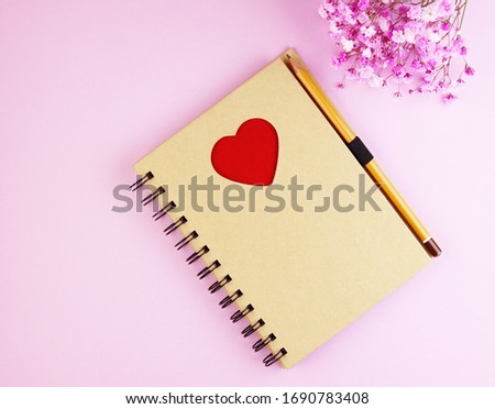 brown notebook with flowers on a pink background. Notepad with a red heart and pencil on a pastel background. purple spring flower bouquet with notebook