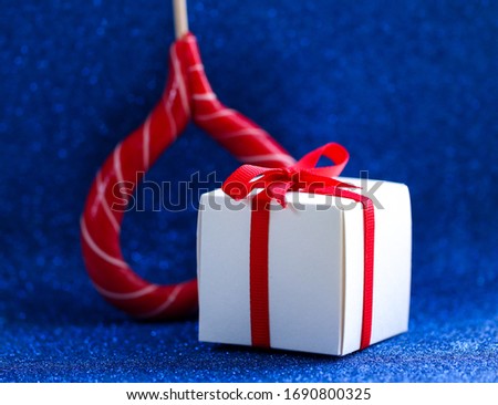 White gift box tied with a red ribbon on a blue background. Gift.