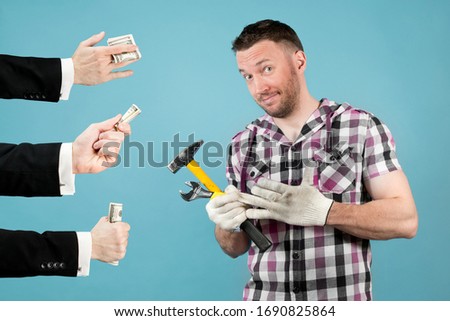 a hard worker with tools in his hands pulls a protective glove from his hand and smiles because the hands of handsome men hold out money to him. highly paid labor Royalty-Free Stock Photo #1690825864