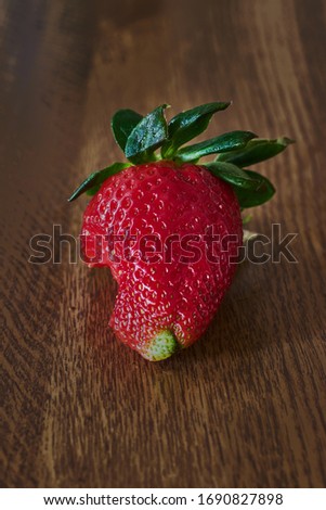 Strawberry with a bite on a wooden table