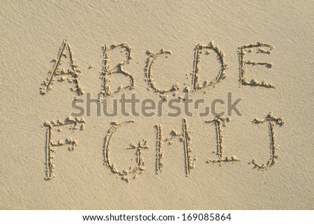 alphabet letters handwritten in sand on beach Royalty-Free Stock Photo #169085864