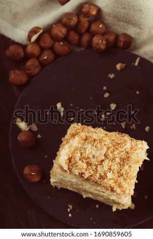 Sweet fresh creamy cake with whole nuts on the black stone plate