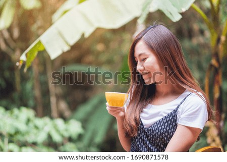 Closeup image of a beautiful asian woman holding and drinking hot coffee in the outdoors