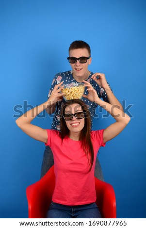 woman and man watching a movie with 3D glasses and eating popcorn