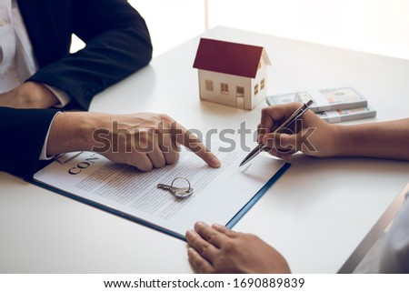 New home buyers are signing a home purchase contract at the agent's desk.