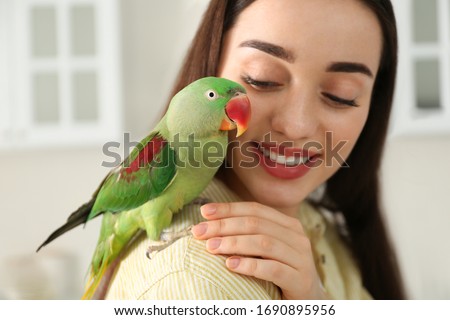 Young woman with Alexandrine parakeet indoors, closeup. Cute pet Royalty-Free Stock Photo #1690895956