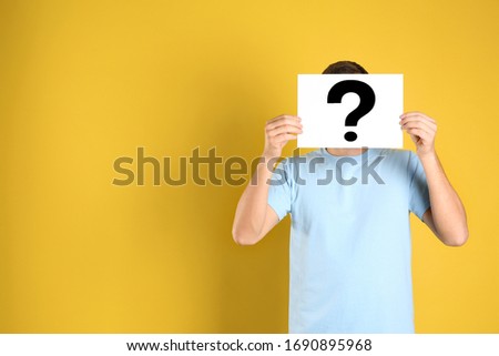 Man holding paper with question mark on yellow background, space for text