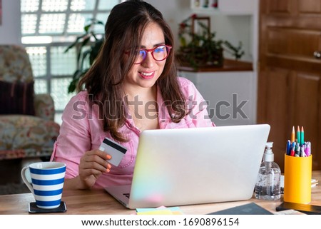 Real woman at home shopping online with a computer during the coronavirus quarantine, covid 19. antibacterial gel, coffee