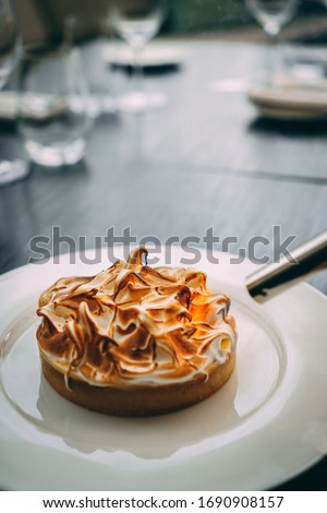 Burning meringue with traditional lemon tart on a table