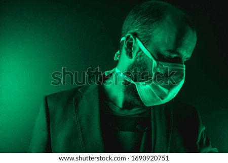 Looking to the right of A young Caucasian man with a scarf in the coronavirus pandemic with a green background, Covid-19