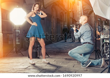 Photo shoot of young female model with professional photographer on city street