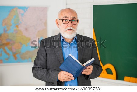 education in retro school. bearded man give marks in diary. write notes in book. senior teacher make notes. teacher of geography. classroom with map and blackboard. back to school.