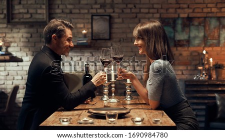 Cheerful happy couple drinking wine and having romantic dinner at home. Home date night, clinking wine glasses. Royalty-Free Stock Photo #1690984780