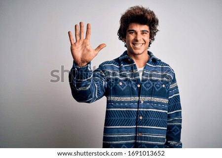 Young handsome man wearing casual shirt standing over isolated white background showing and pointing up with fingers number five while smiling confident and happy.