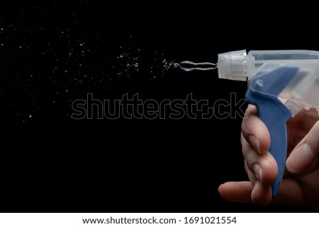 a small jet of water from the sprayer in the hand of a girl on a black background close up
