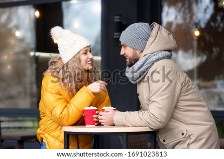 Happy young couple drinking hot cocoa in cafe outdoors