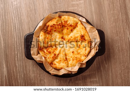 Khachapuri is a traditional Georgian dish. Suluguni pie or meat pie. on a wooden tray. on a background of wood.