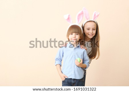 Cute little boy and girl in rabbit ears and with an Easter basket on a colored background. Easter background with place to insert text. Family Easter traditions.
