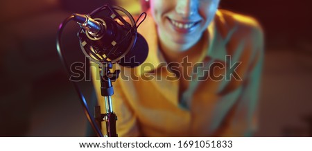 Young smiling radio host talking into the microphone, communication and entertainment concept