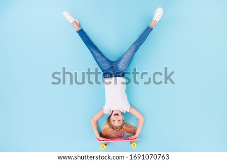 Top above high angle view full body photo of positive girl sporty kid ride longboard upside down show tongue out wear white clothes lay isolated over blue color background