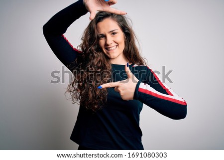 Young beautiful woman with curly hair wearing casual sweater over isolated white background smiling making frame with hands and fingers with happy face. Creativity and photography concept.