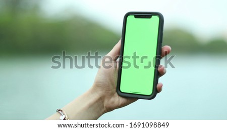 
Hand holding smartphone device with greenscreen. Chroma key, close up woman hand holding phone with vertical green screen