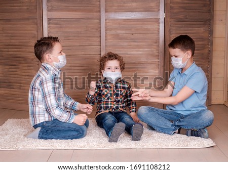 three boys play at home in medical masks during quarantine. family quarantine during the coronavirus pandemic
