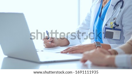 Doctor and patient couple are discussing something,sitting on the desk.
