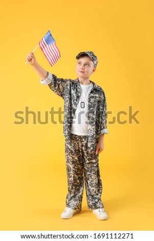Cute little soldier with USA flag on color background