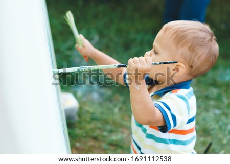 boy holding brush during painting at yard