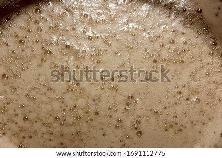
Coffee foam top view. Cup of coffee close-up on a black background. Latte isolated on black with place for text.