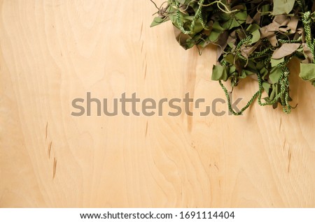 partly green-brown camouflage net on the background of a wood plate. graphic template for decoration on a military and hunting theme.