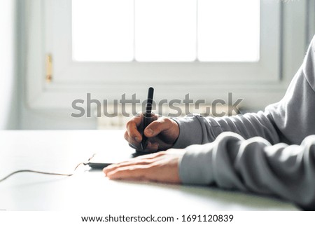 Young man designer working using graphics tablet at home office