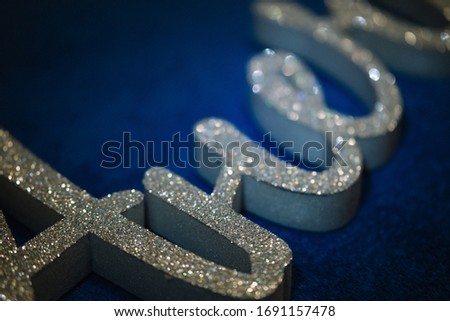Letter and word from gray extruded polystyrene foam painted in silver glitter. decor lies on a dark blue background. blank for decoration, logo making
