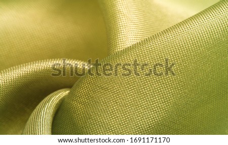 Background texture, silk fabric, shiny green light green color, with a small abstract print of rock paintings.