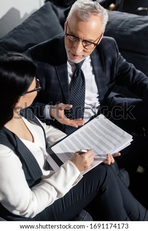 high angle view of businessman and businesswoman talking and doing paperwork