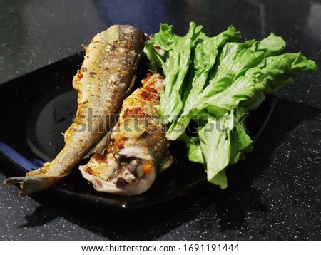 Pictured is a plate with fried fish and spinach leaves