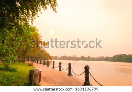 Lake side public park in summer evening. Garden footpath park lane illuminated by sunset sunlight. Red and orange color in landscape scene. Sun setting. Dhakuria lake Town Kolkata West Bengal India 