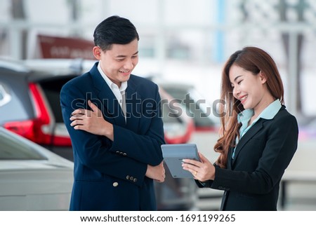 Pictures of Asian customers and happy salespeople who buy new cars that enter into sales agreements with car dealers at car dealers.