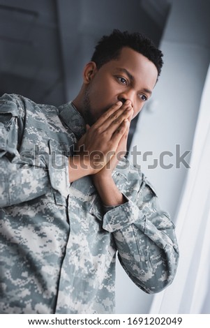 Worried african american soldier in military uniform at home