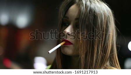 
Pretty girl lighting a cigarette at night in nightlife