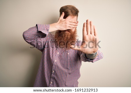 Handsome Irish redhead business man with beard wearing glasses over isolated background covering eyes with hands and doing stop gesture with sad and fear expression. Embarrassed and negative concept.