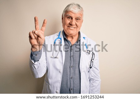 Senior handsome hoary doctor man wearing coat and stethoscope over white background showing and pointing up with fingers number two while smiling confident and happy.