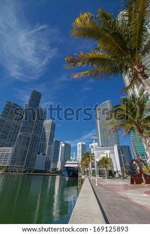 Miami downtown river cityscape along the Brickell area. Wide angle shot with palms, skyscrapers and blue sky