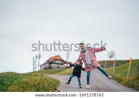 picture of lovely young caucasian female with pretty face, short dark hair, big eyes walks with her child and rejoices