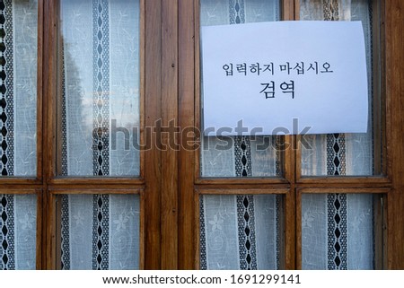 a sign with the inscription: "Do not enter, Quarantine", write on in Korean language attached on a window