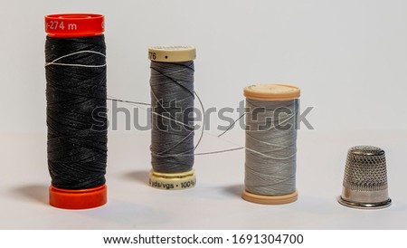 Composition of three spools of sewing thread tied together like a hug and a dressmaker's thimble Royalty-Free Stock Photo #1691304700