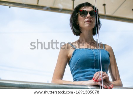 lovely slim girl in sunglasses stands thoughtfully at the bus stop