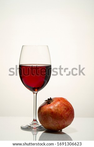 Glass with red wine and pomegranate on a light background